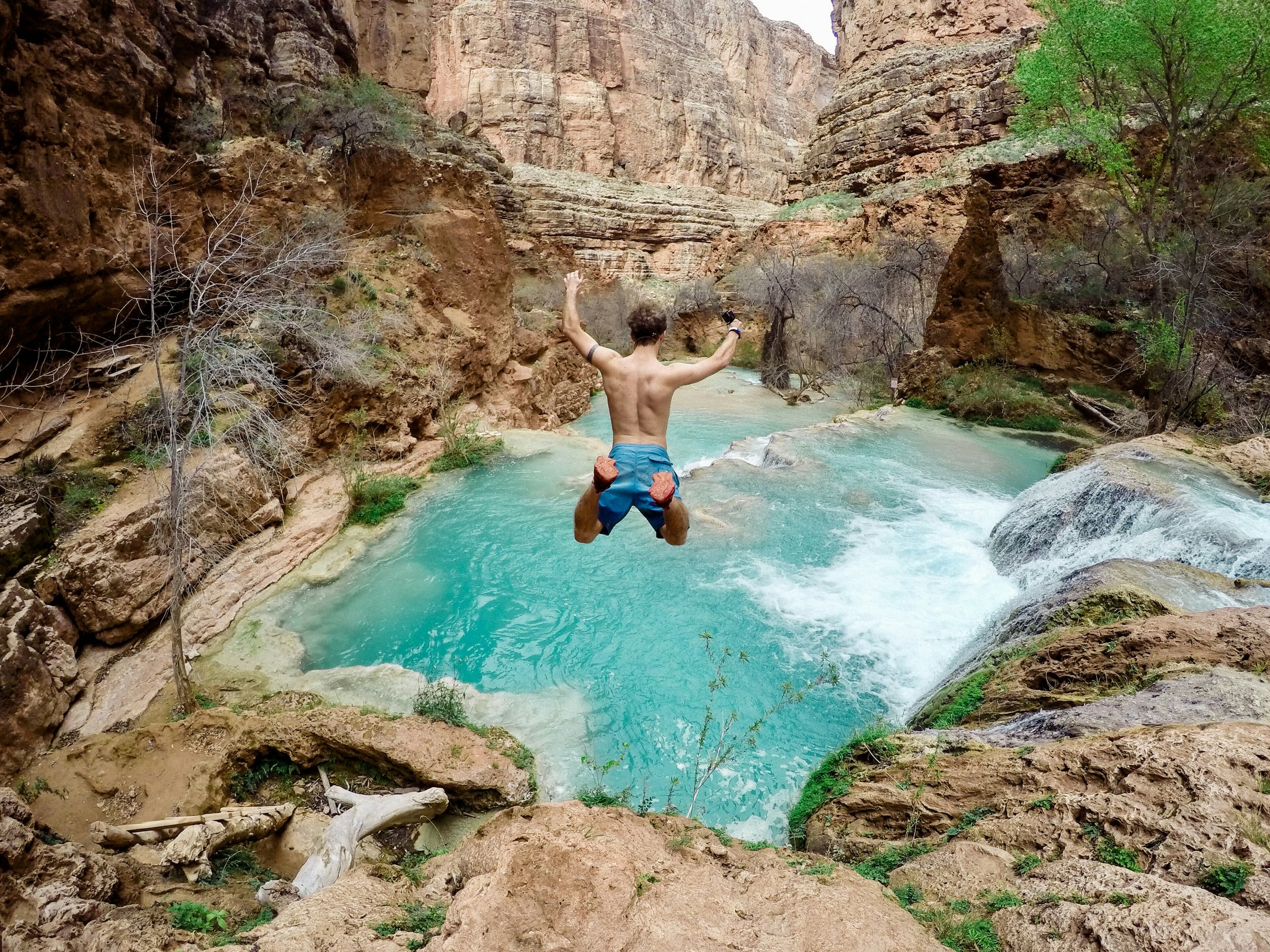 man jumping into waterfall