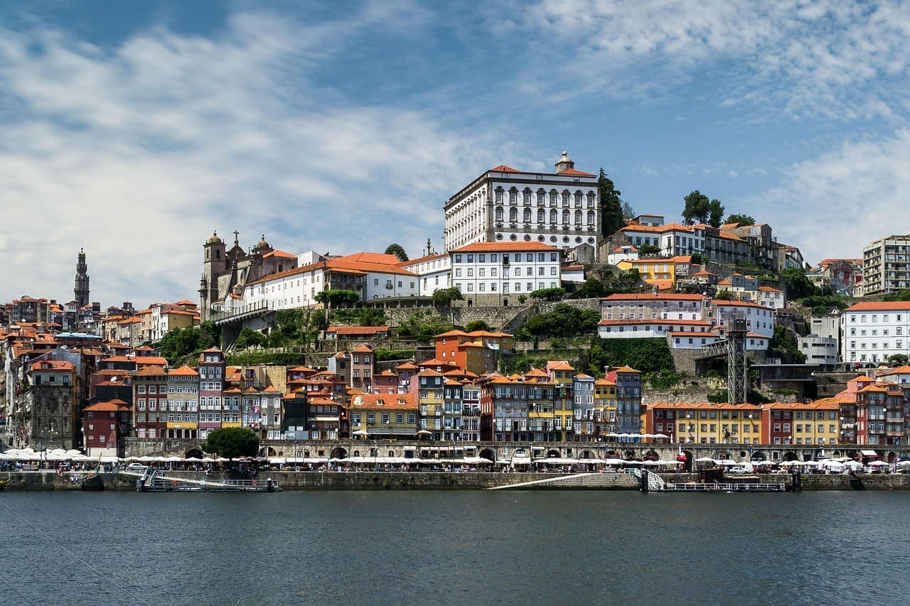Colourful houses along the riverside in Porto with the Douro River in front and historic buildings rising up the hill.