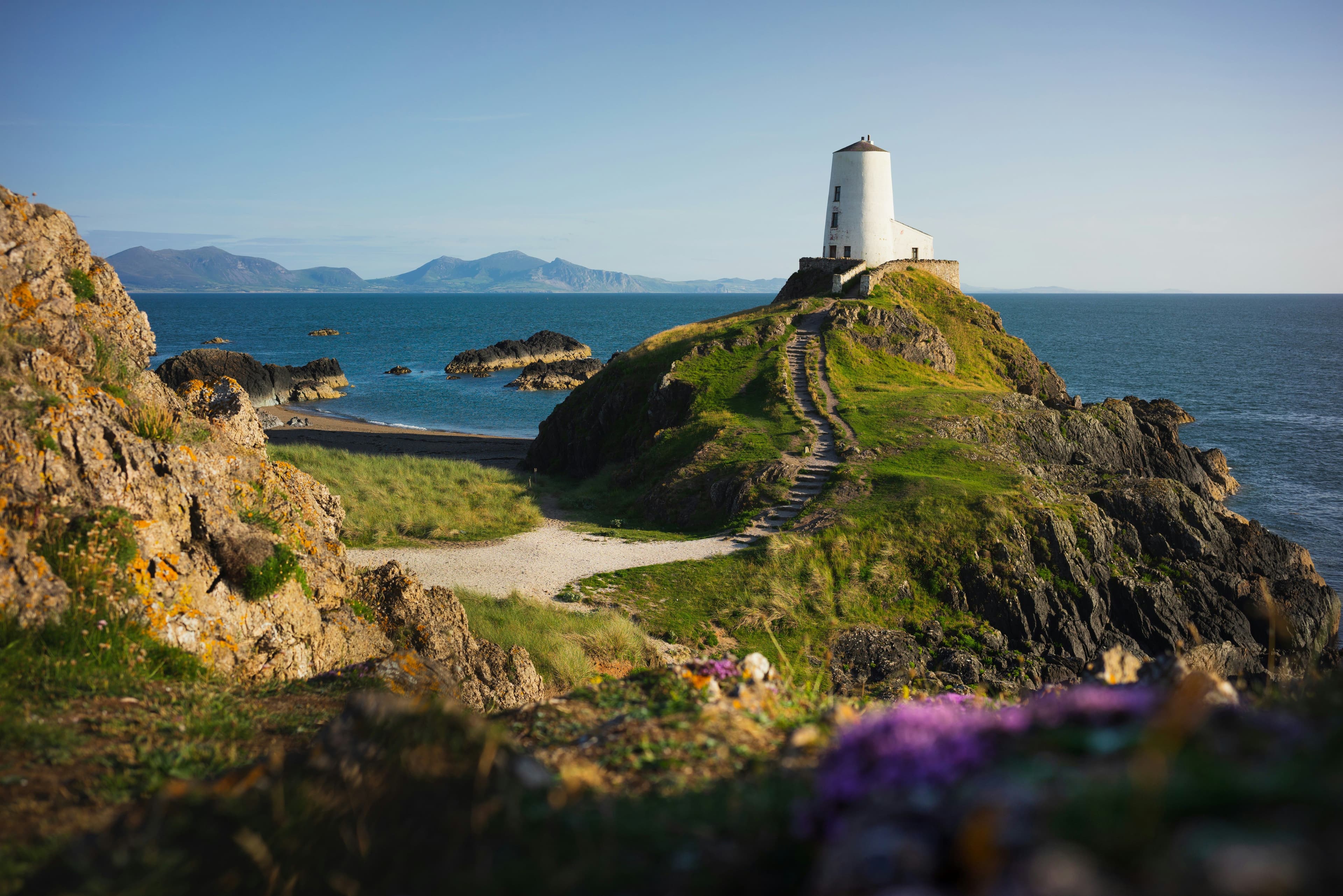 Green hill landscape next to the ocean with a lighthouse